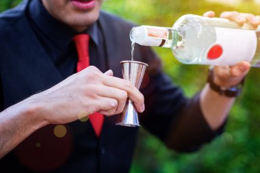 Barmenin elindeki sürahi jigger, eğlenmek için servis edilen kokteyl likörünü damlatıyor ve eğleniyor. 