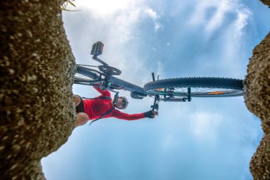 Dağ bisikletiyle bisikletçinin alt görüntüsü sürerken engelleri aşmaya çalışır