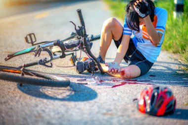 accident clashed on young woman bicyclist in hurt and injured at knee of leg and arms, after accident clashed, with mortal wound and bleeding of blood flow on the surface of street road