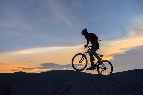 silhouette of a man riding a mountain bike up a hill, extreme sport mountain biker