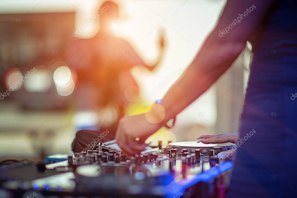 DJ takes control platter spindle of rhythm music with Controller and mixer dash board, playing the song at the party, adjusting the music with the controller, fun of music and light colors, Music & Event controller sound