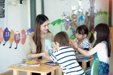 Öğretmenler ve bir grup uluslararası çocuk derse katılıyor ve birlikte öğrenmenin keyfini çıkarıyorlar.