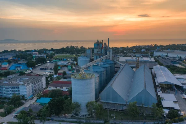 feed mill factory in production line at sunset and sea view in back ground, factory produce line of industrial estate area locate in middle of the city town against air pollution