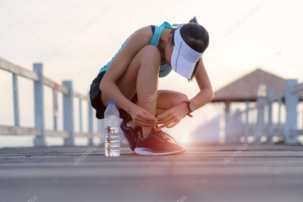 lace of running shoe on the wooden bridge by woman jog runner, daily exercise workout running at light of sunset 