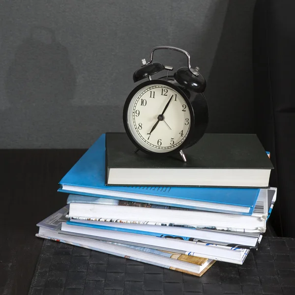 Черный будильник на черно-белой полосатой салфетке, показывающий 7 часов на тумбочке — стоковое фото