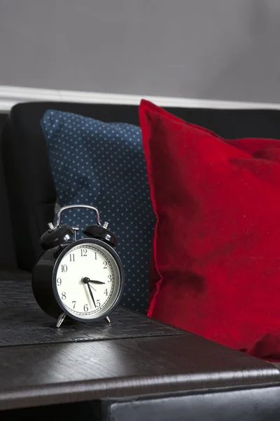 Reloj despertador negro en una servilleta rayada en blanco y negro que muestra las 7 en punto en una mesita de noche — Foto de Stock