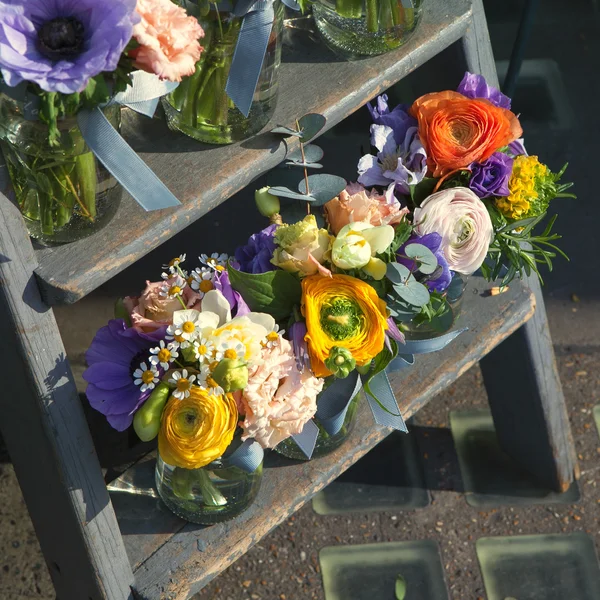 Rose, chamomile, eucalyptus, anemone, freesia in glass jar on the steps — Stock Photo, Image