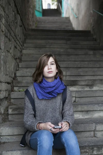 Location shot of a lonely sad teen girl sitting on steps with her backpack — Stock Photo, Image