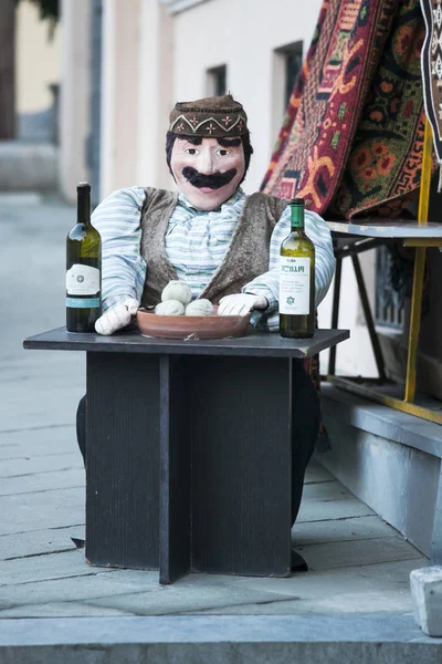 Georgian doll in national dress sitting at table with khinkali in Old Tbilisi. — Stock Photo, Image