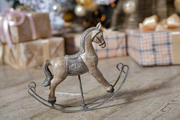 small wooden rocking horse under the Christmas tree with gifts