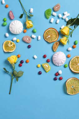 Marshmallow, şeker, şeker, tatlılar ve gofret koni içinde mavi zemin üzerine düşen kuru bardağı portakal