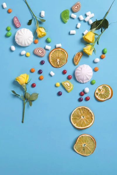 Marshmallows, doces, geléias, doces e canecas secas laranjas caindo em cone wafer sobre fundo azul — Fotografia de Stock