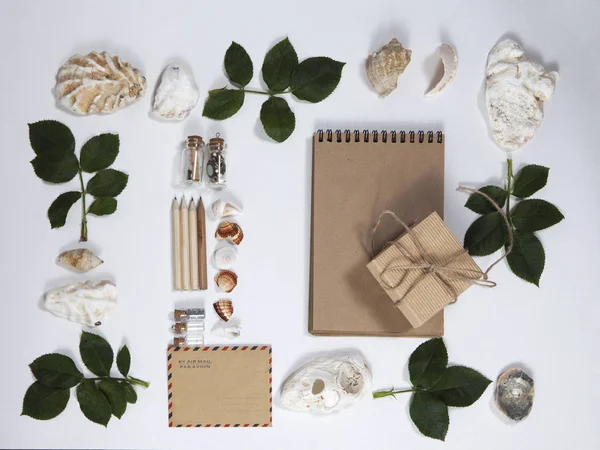 Rahmen aus den Blättern von Rosen und Muscheln auf weißem Hintergrund. Erinnerung an den Sommer — Stockfoto