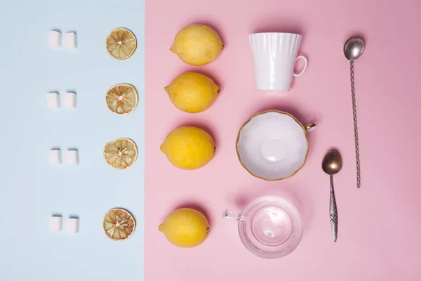 Um conjunto de chá. Açúcar refinado, limão, laranja, xícaras e colheres como ornamento em papel rosa e azul — Fotografia de Stock