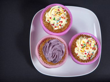 Beyaz ve mor siyah arka plan üzerine krem ile cupcakes,