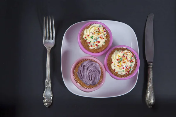 白と紫黒の背景上にナイフとフォークにクリームのカップケーキ, — ストック写真