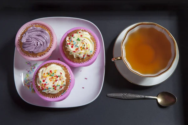 Os cupcakes com creme branco e violeta com colheres no fundo preto — Fotografia de Stock