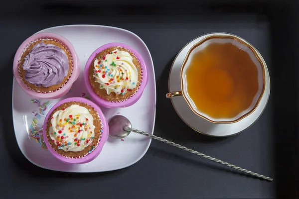 Os cupcakes com creme branco e violeta com colheres no fundo preto — Fotografia de Stock