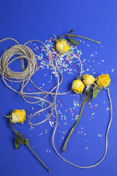 玫瑰用绳子和洒在蓝色背景的蛋糕 — 图库照片