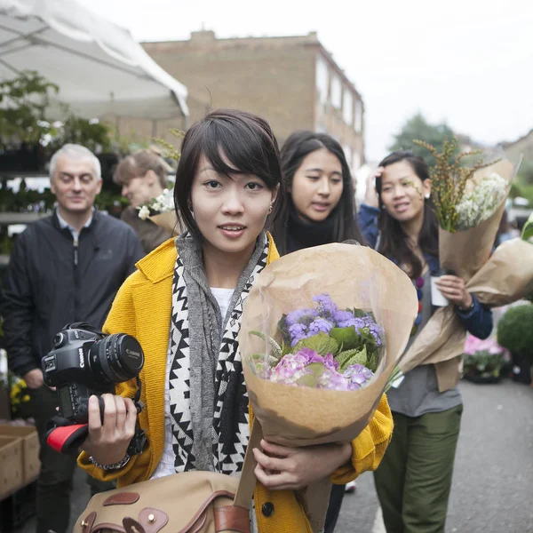 People gather at Columbia Road Flower Market in the East End of London. This market is as much social as it is about buying — Stock Photo, Image