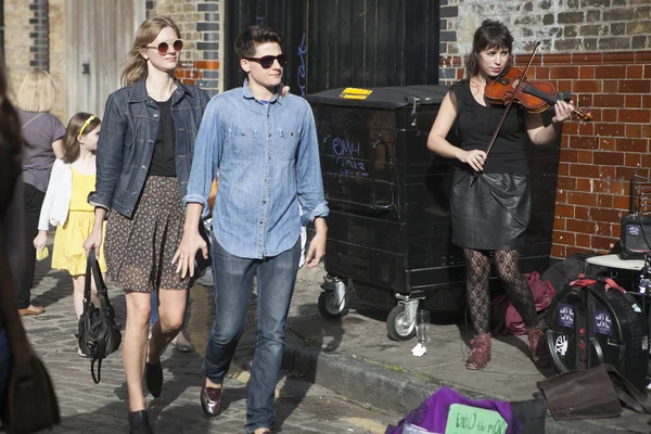 Sunday flower market on Columbia Road. Local sitting on sidewalks, drink wine, eat and listen to the street musicians. Some of them dancing. — Stock Photo, Image