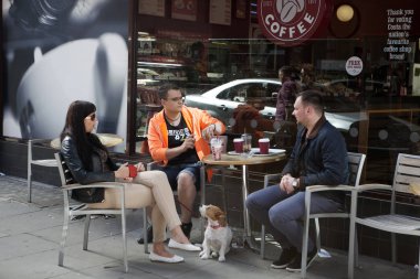 İki adam ve bir köpek ile uzun saçlı esmer bir kadın sokak bir kafede oturan ve söz