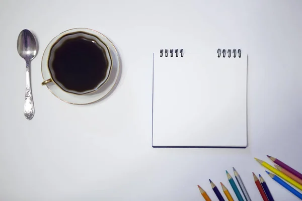 Kopp kaffe och ett tefat, pennor på en vit bakgrund — Stockfoto