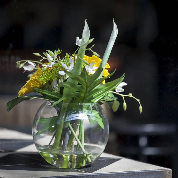 Den konstgjorda buketten av bladen av monstera Alismatales, gerbera Transvaal daisy och solros i en vas på bordet — Stockfoto