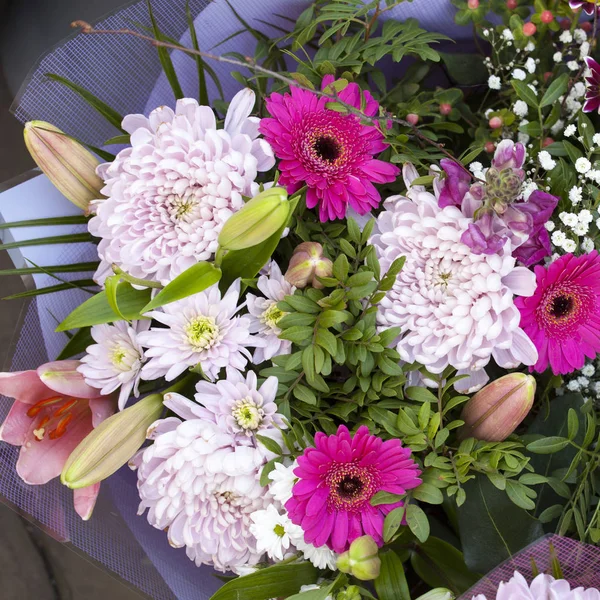 The Bouquet of chrysanthemums, gerberas, chamomiles in paper packing — Stock Photo, Image