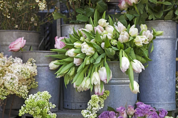 O balde com um buquê de tulipas brancas e um vaso com rosas vermelhas como decoração para a entrada da casa — Fotografia de Stock