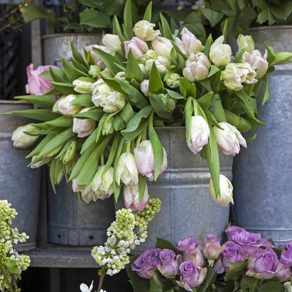 O balde com um buquê de tulipas brancas e um vaso com rosas vermelhas como decoração para a entrada da casa — Fotografia de Stock