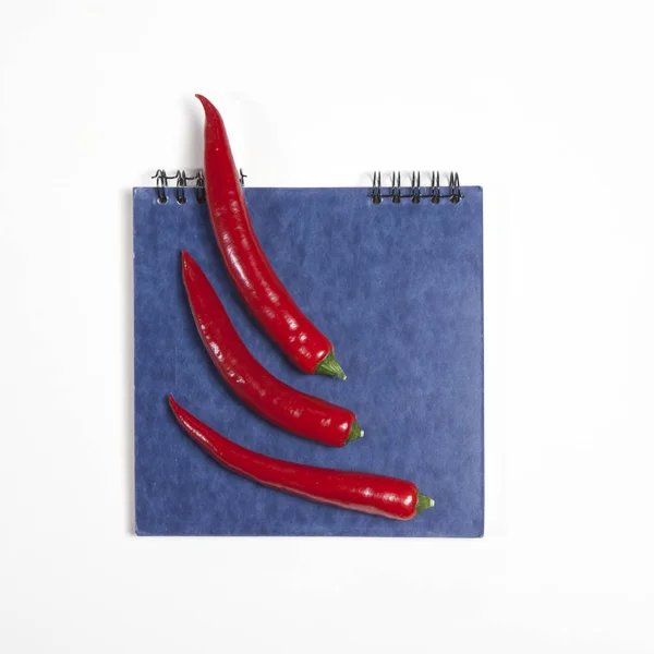 De postkaarten voor recepten. Blauwe schetsblok en rode peper als een frame op een witte achtergrond. — Stockfoto