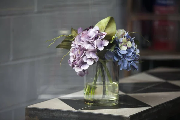 Bouquet artificiale di ortensie rosa e viola su un tavolo in un caffè. Il sole dà ombre — Foto Stock