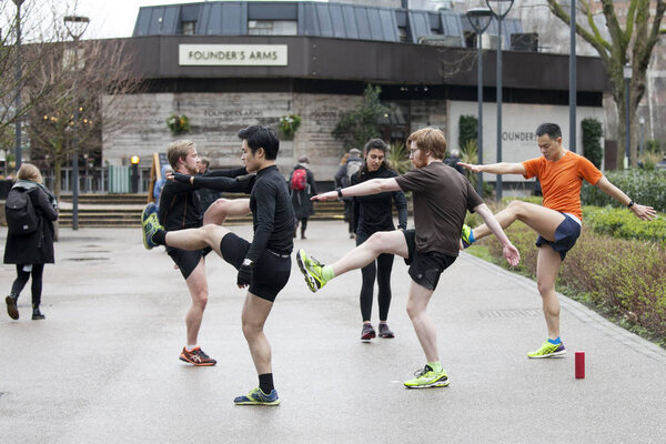 Men in sports uniforms do exercise on the street