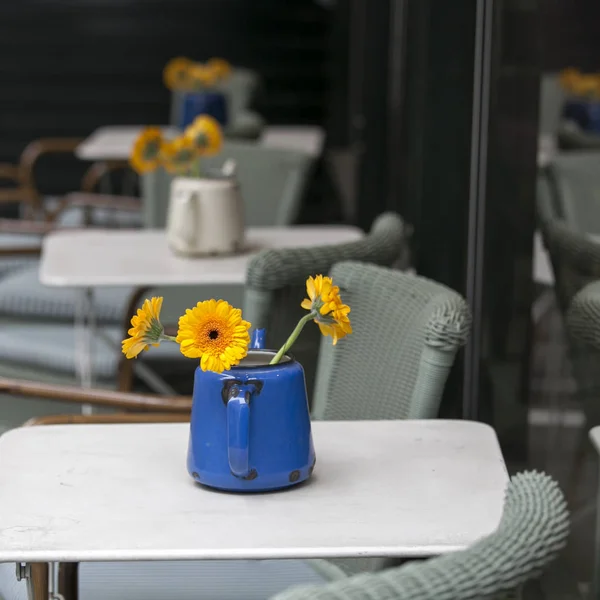 Gerberas naranjas en tetera azul con óxido como decoración de mesa en un café —  Fotos de Stock