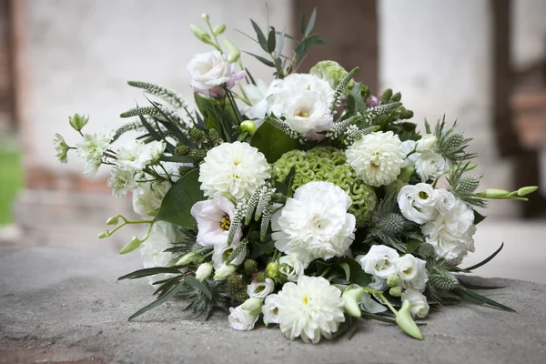 Il bouquet nuziale nei toni del bianco di lisianto, rose, dalie ed eucalipto adagiato su pietra antica pavimentazione — Foto Stock