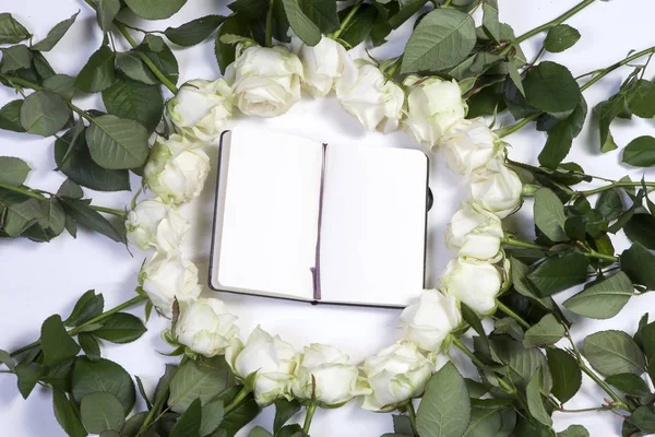 Un carnet avec une rose blanche sur fond blanc avec un espace vide pour les notes . — Photo