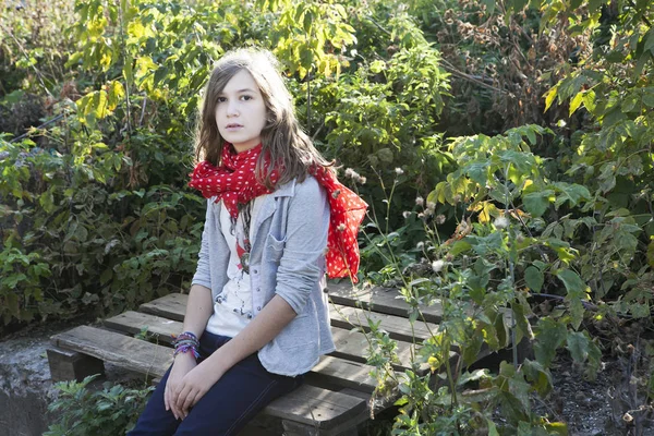 Der schöne junge Teenager sitzt auf einem Baumstamm — Stockfoto
