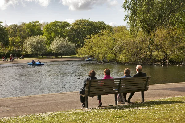 Bir göl kenarında bir bankta oturan yaşlı çift