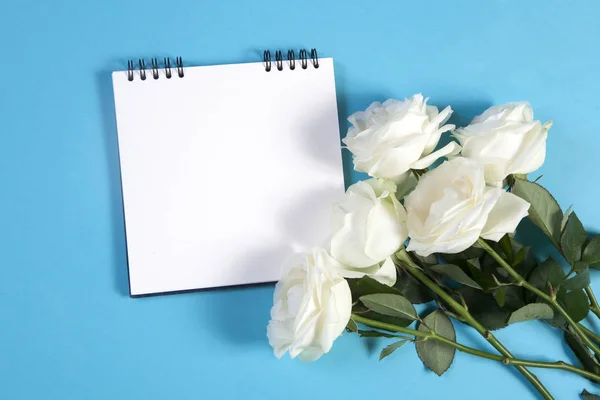A rugók notebook egy üres helyet a jegyzeteket kék alapon fehér rózsával. — Stock Fotó