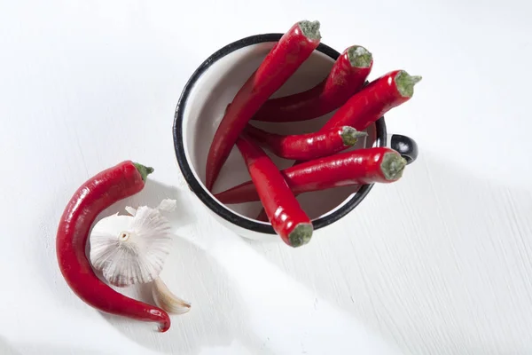 De pittige rode peper in een kopje wit geëmailleerd. Herfst recepten. Kopiëren van ruimte — Stockfoto
