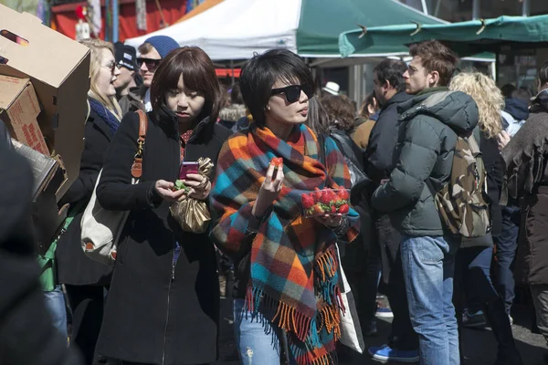 Two beautiful Asian women with strawberries are making their way through the crowd in the market — Stock Photo, Image