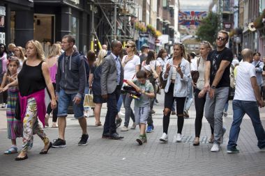 Çok renkli bir kalabalık Carnaby Street boyunca yürür. Carnaby Street Londra ana alışveriş caddelerinden biri.