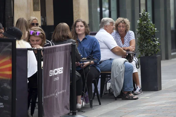 İnsanlar Piccadilly Circus yakınındaki sokak bir kafede oturuyor
