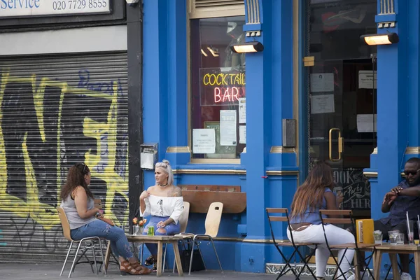 İnsanlar pub dışında oturuyor