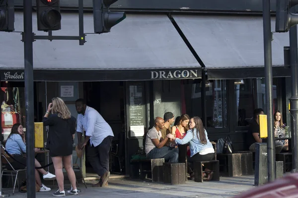 İnsanlar pub dışında oturuyor