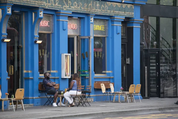 İnsanlar pub dışında oturuyor