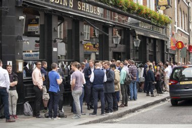 Rengarenk kalabalık pub dışında oturur, bira içiyor, arkadaşlarıyla konuşuyor. Semt pazarı