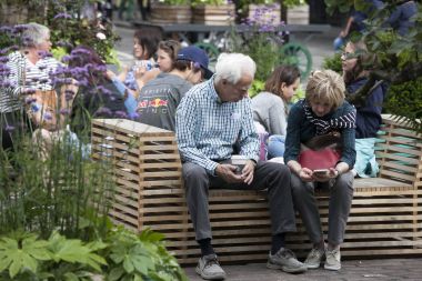 Yaşlı bir çift seyir telefon bir bankta oturuyor. Küçük Bahçe Covent Garden center.