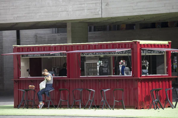 Carro rosso trasformato in un caffè di strada vicino al Teatro Nazionale. Una donna aspetta il suo caffè, seduta su uno sgabello alto . — Foto Stock